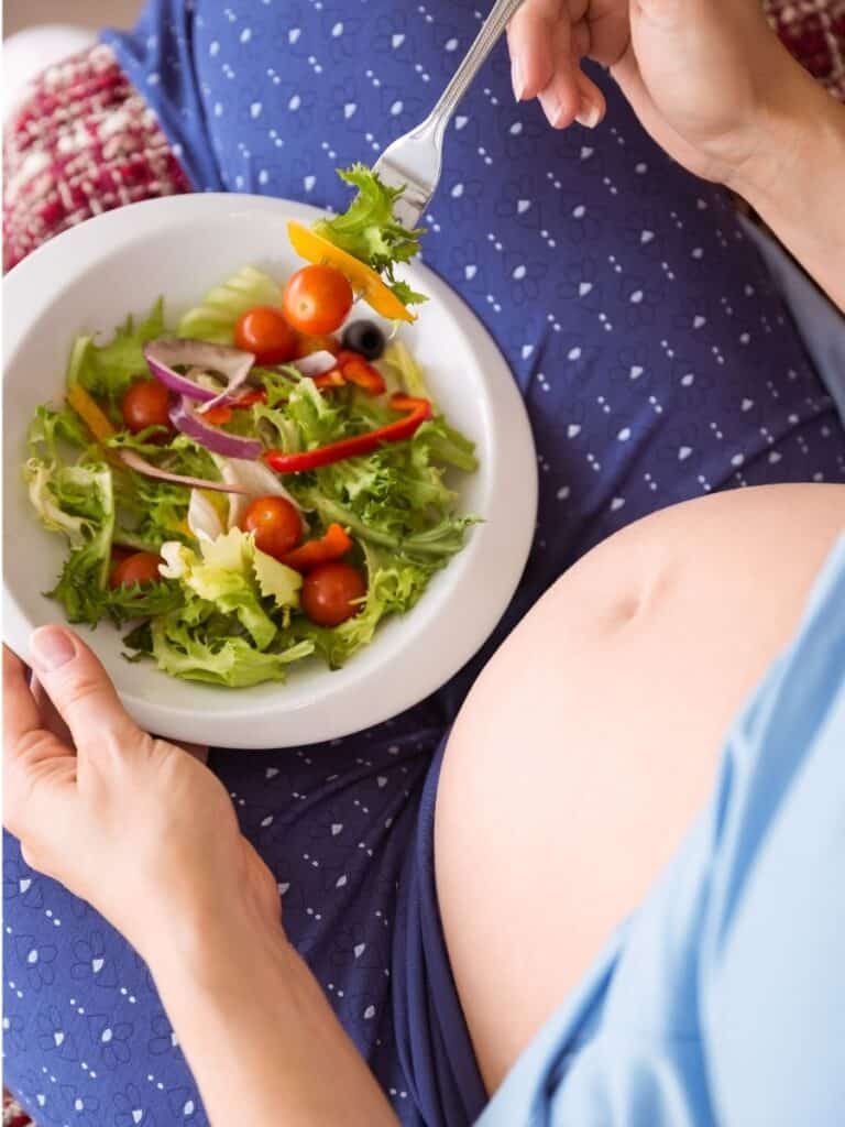 pregnant woman eating a healthy salad