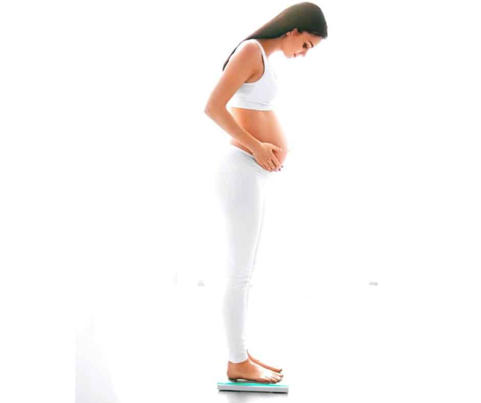 pregnant woman on scale weighing herslelf